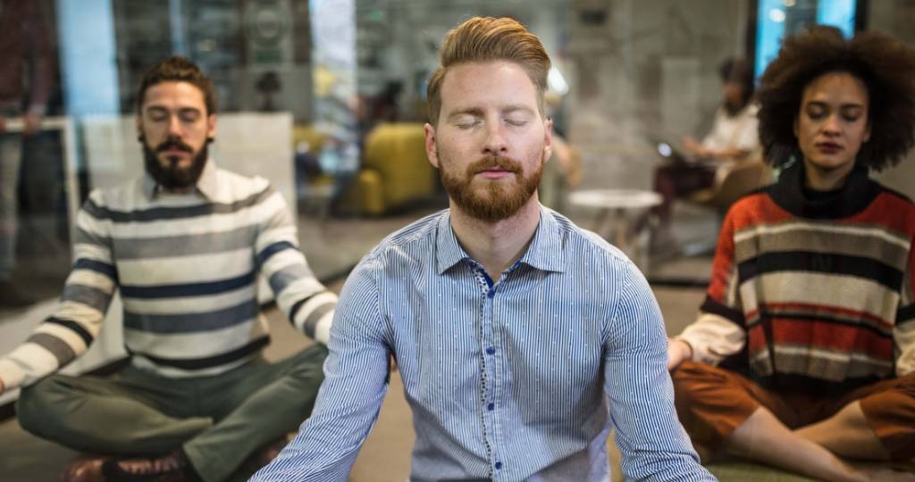 Trois personnes qui font du yoga au burea