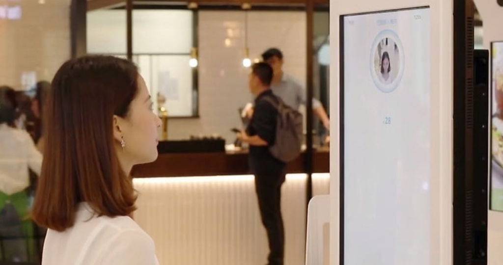 Une femme devant un borne de paiement AliPay