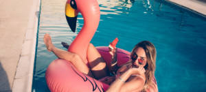 Une femme dans une piscine avec un bouée en forme de flamant rose