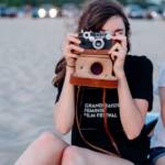 Deux jeunes adolescentes prennent des photos à la plage sur leur téléphone et un appareille photo