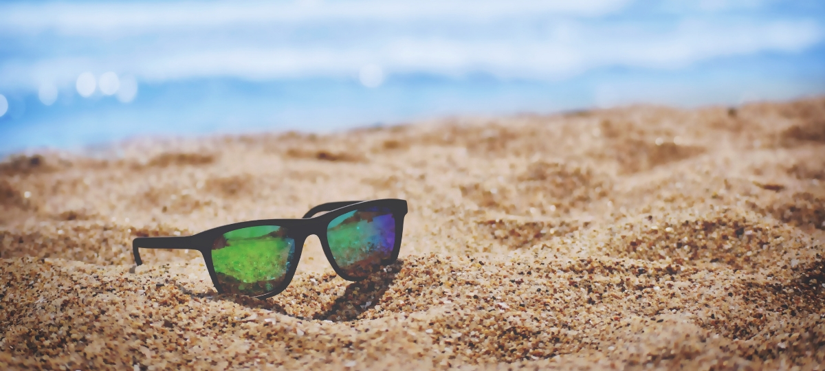 Les meilleures villes où draguer cet été Une paire de lunette de soleil sur le sable