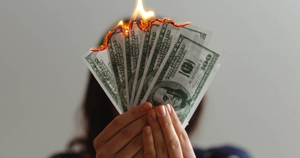Une femme qui tient des billets de dollars en train de bruler