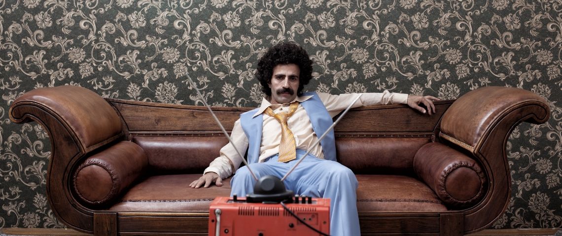 Comment attirer les talents quand on est une marque jugée ringarde ou austère ? Un homme déprimé sur son canapé, dans une décoration très seventies.