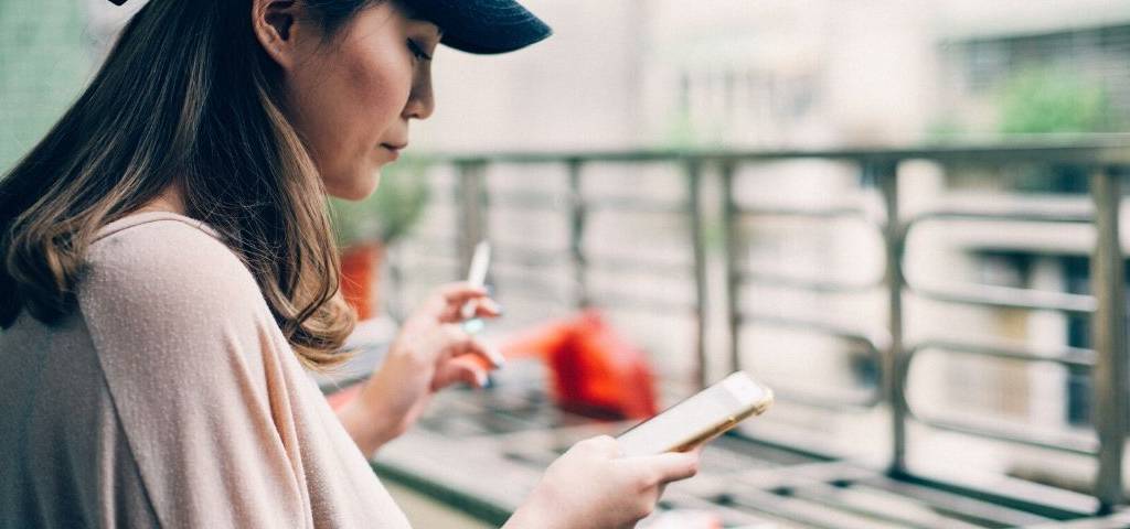 Social-ads-facebook-linkedin Une femme fume une cigarette en consultant son téléphone