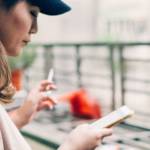 Une femme fume une cigarette en consultant son téléphone