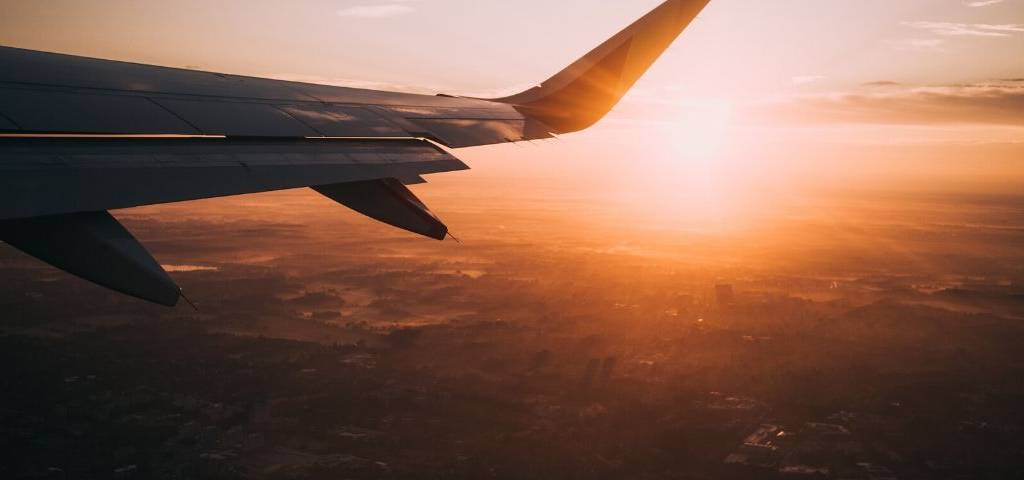 Phtot de l'aile d'un avion au soleil couchant
