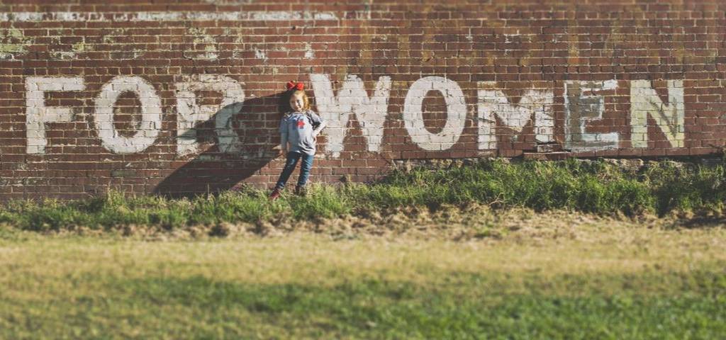 Une petite fille devant un mur en brique