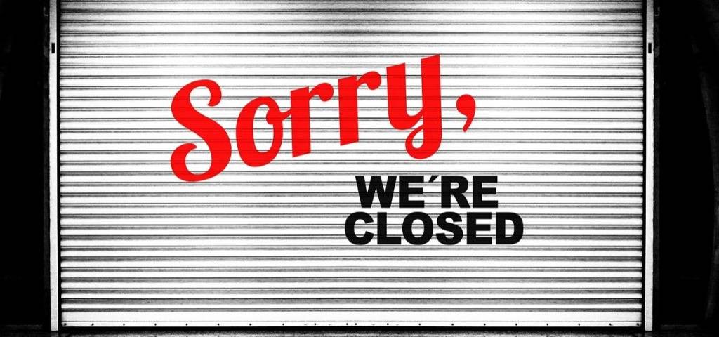 Rideau fermé d'une boutique avec le message : Sorry We're Closed