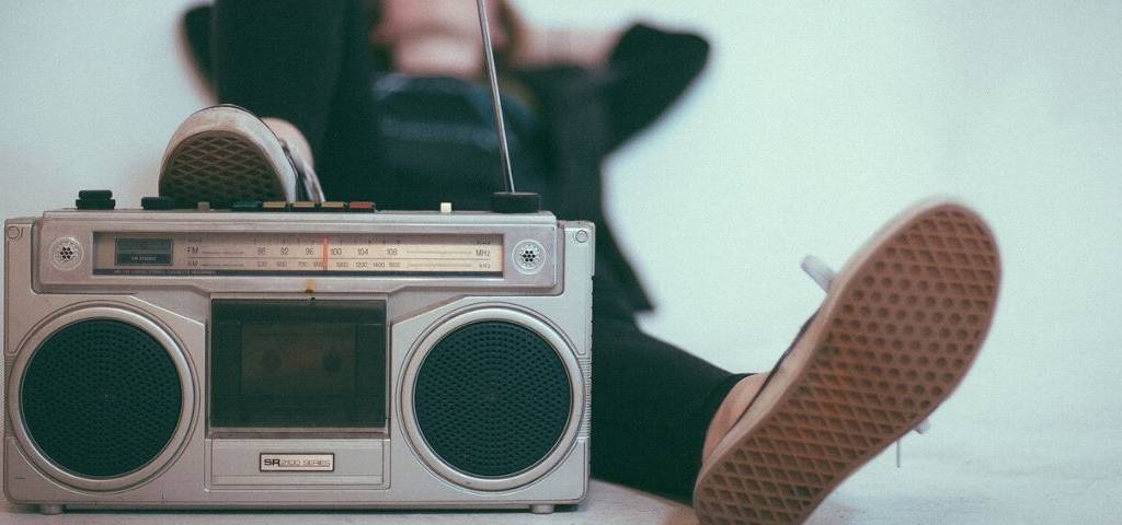 Visuel d'un ancien poste de radio, avec une jeune femme allongée qui a le pied dessus