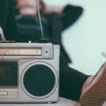 Visuel d'un ancien poste de radio, avec une jeune femme allongée qui a le pied dessus