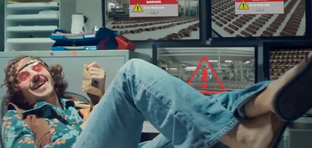 Capture d'écran de la vidéo : un technicien en mode hippie, les pieds sur son bureau