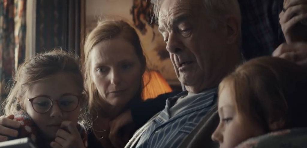 Capture de la publicité d'Apple ppur Noël, avec une famille réunit en trai nde regarder un diaporama sur l'Ipad