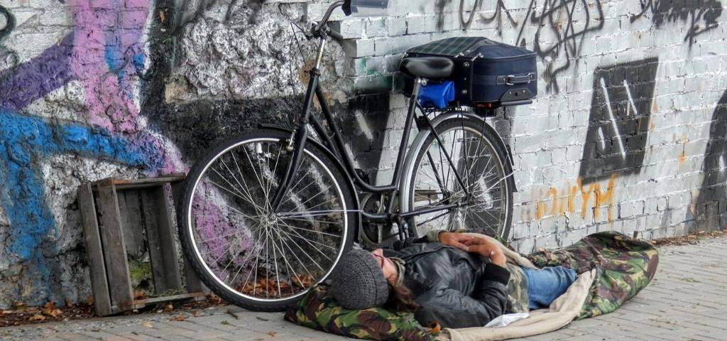 SDF dormant au sol, à côté de son vélo