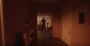 Homme nu de dos au fond d'un couloir, derrière un rideau ajouré