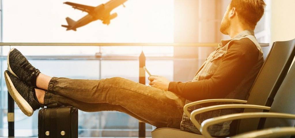 Homme regardant un avion s'envolé assis dans un hall d'aéroport