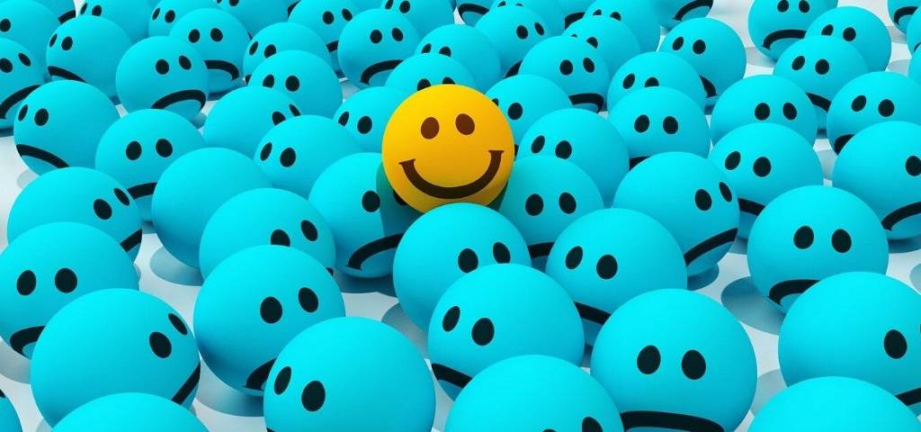 Emojis tristes avec un emojis souriant qui se distingue du lot