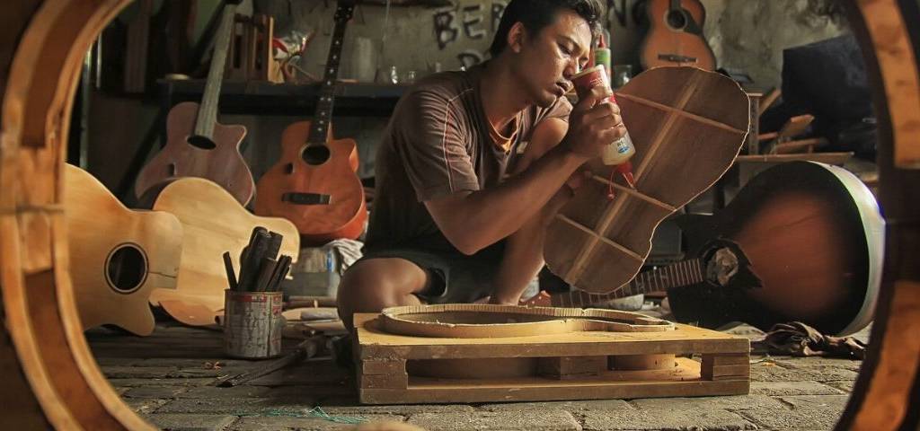 Jeune artisant fabricant une guitare