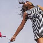 Jeune fille sautant en l'air avec un ballon rouge en forme de coeur dans la main droite