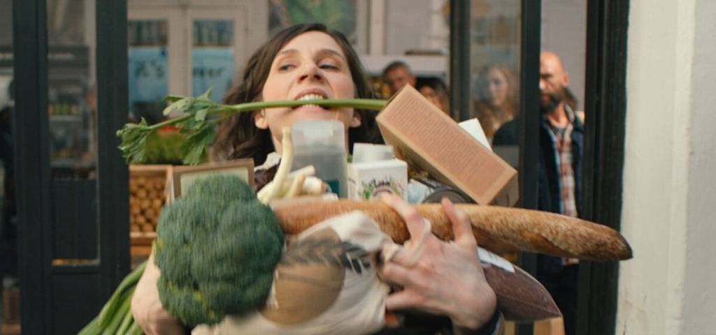 Femme tenant ses achats dans ses bras à la sortie d'une magasin, faute d'avoir oublié son sac réutilisable