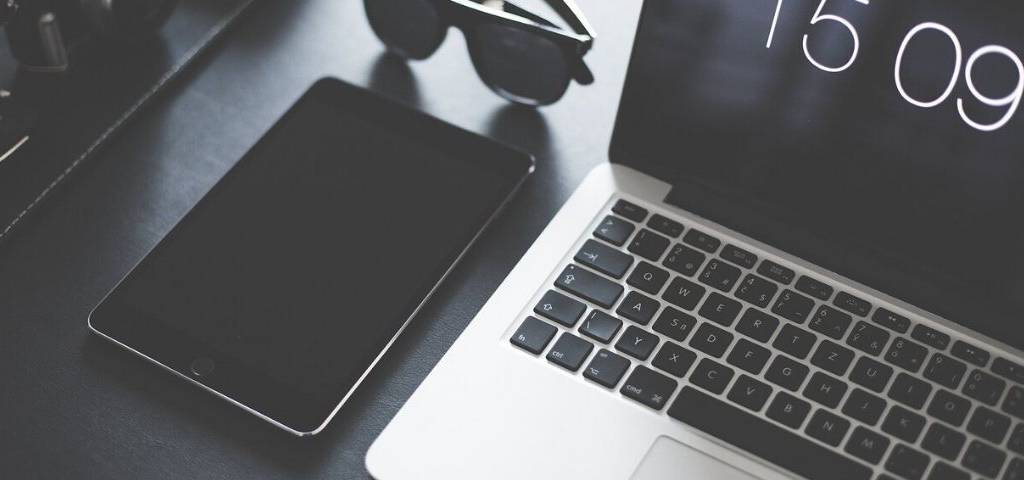 Ordinateur et tablette sur une table avec une paire de lunette noires sur le côté