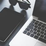 Ordinateur et tablette sur une table avec une paire de lunette noires sur le côté