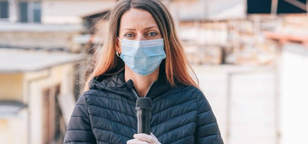 Une journaliste avec un masque et un micro
