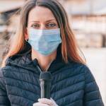 Une journaliste avec un masque et un micro