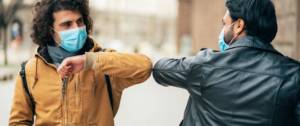 Deux personnes se saluent avec un masque
