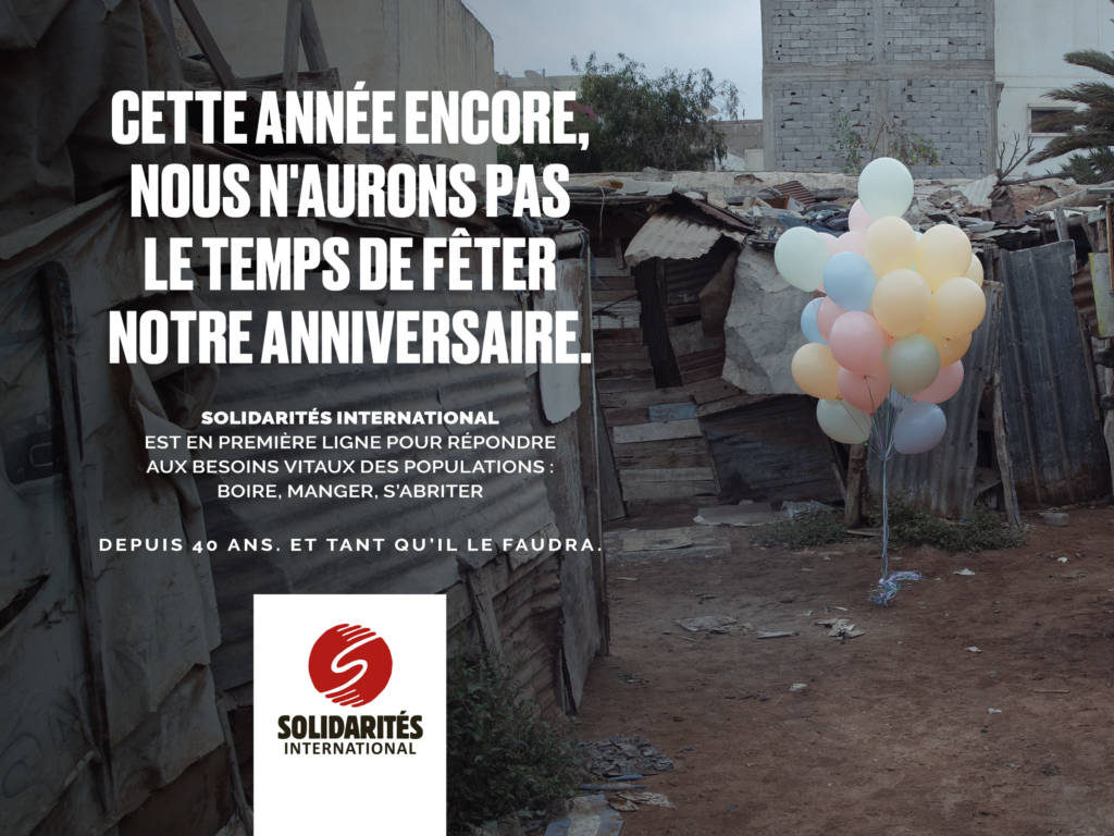 Solgan de la campagne : Cette année encore, nous n'aurons pas le temps de fêter notre anniversaire. Avec en arrière plan un des ballons de baudruches accrochés à des débris d'immeubles
