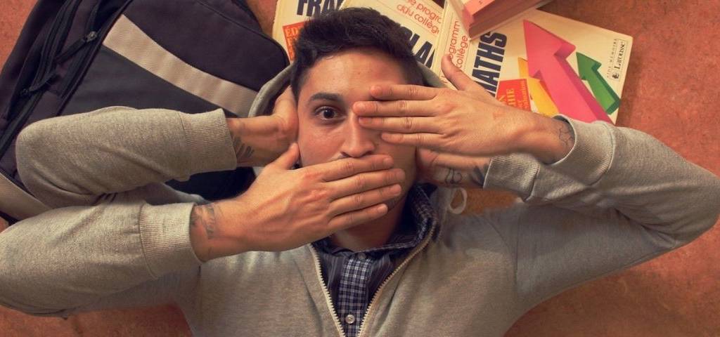 Jeune homme mettant une main sur ses yeux, ses oreilles et sa bouche