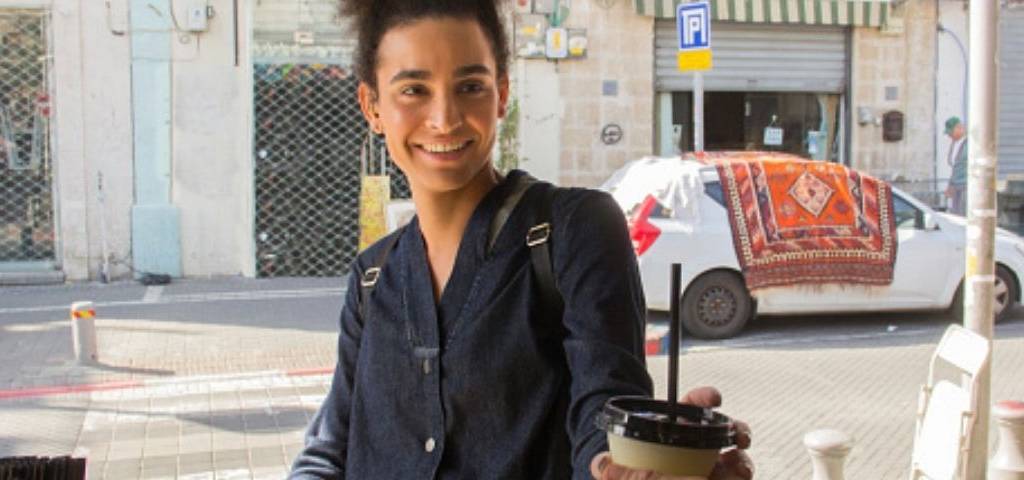 Personne transgenre souriante prenant un café