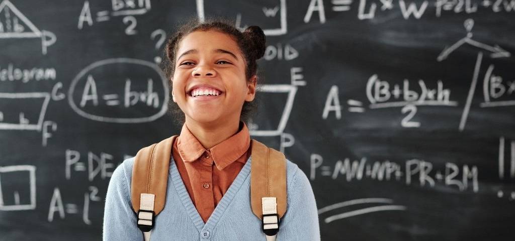 Jeune fille souriante devant un tableau d'école