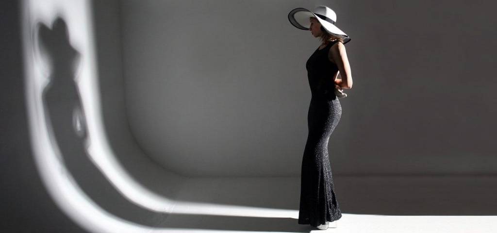 Jeune femme habillée avec une robe haute couture, regardant son reflet dans un mur
