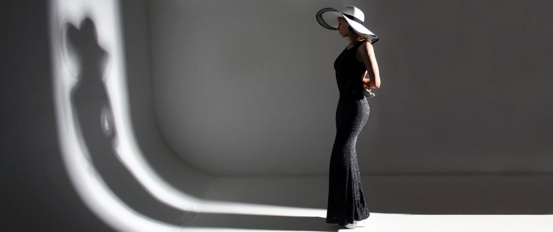 Sup de Luxe s’associe à The Fashion Stories, le média qui raconte la mode et crée un nouveau rendez-vous pour les passionnés de luxe : La Minute Luxe Jeune femme habillée avec une robe haute couture, regardant son reflet dans un mur