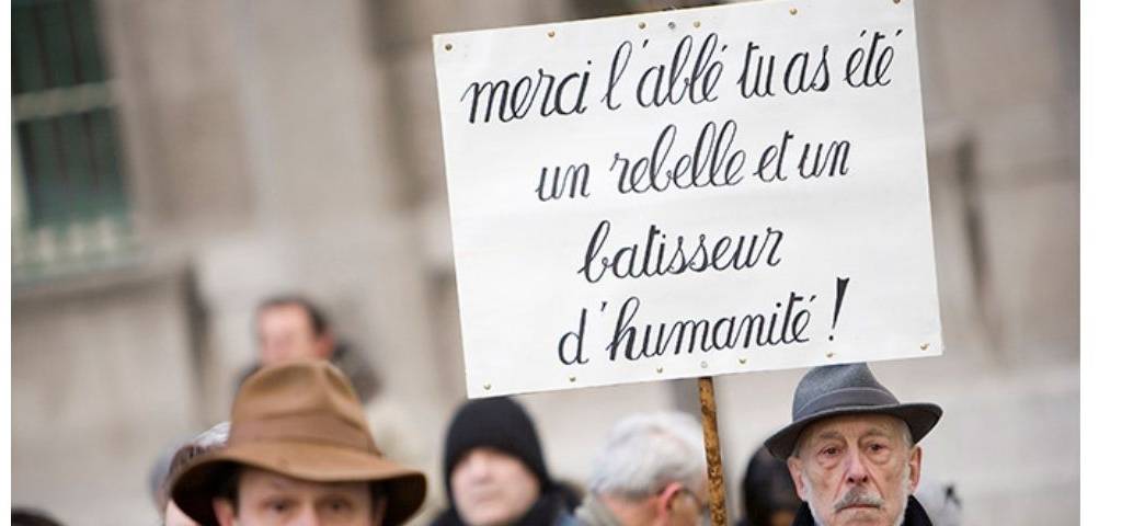 Pancarte : Merci l'abbé tu as été un rebelle et un batisseur d'humanité