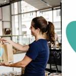 Jeune femme donnant un sac à l'effigie Too Good To go à une autre femme