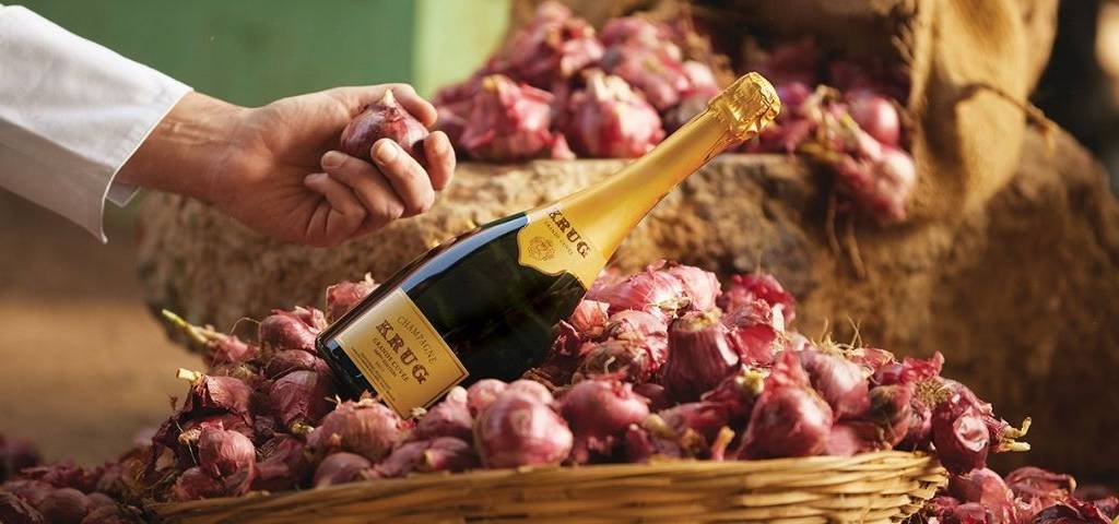 Bouteille de champagne, posée sur un panier avec des oignons