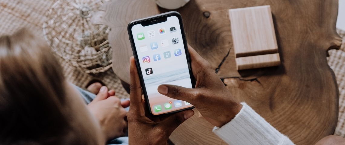 TikTok déploie de nouveaux paramètres de confidentialité pour tous ses utilisateurs âgés de 13 à 15 ans, dont le mode Privé par défaut Ado devant leur smartphone avec le logo TikTok