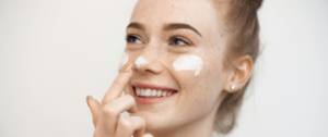 Une femme se met de la crème sur le visage