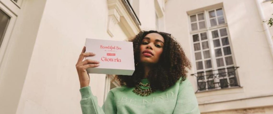 Beautiful Box by aufeminin change de nom et devient Glowria. Une box beauté et un média digital. Jeune femme tenant une box Glowria dans la main
