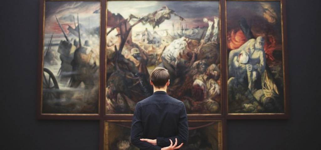 Homme de dos devant un tableau dans un musée