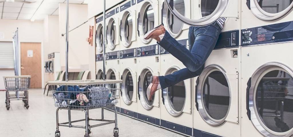 Jeunes femme dans une machine à laver dans une laverie automatique