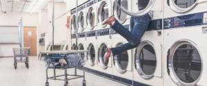 Jeunes femme dans une machine à laver dans une laverie automatique