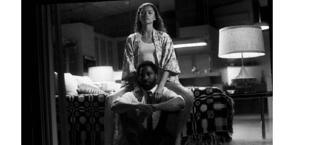 Femme assise au bord du lit, avec un homme devant, assis au sol
