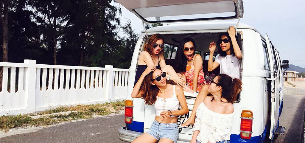 Filles riant assises dans le coffre d'un minibus pr§ès de la plage