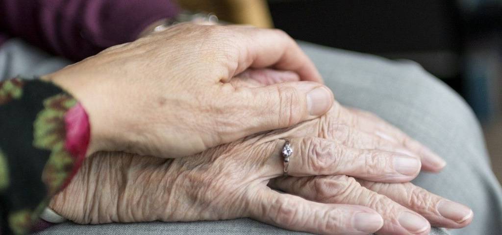 2 mains de personnes âgées, l'un sur l'autre