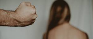Femmes de dos face à un mur, avec un homme au 1er plan qui pointe son poingt vers elle