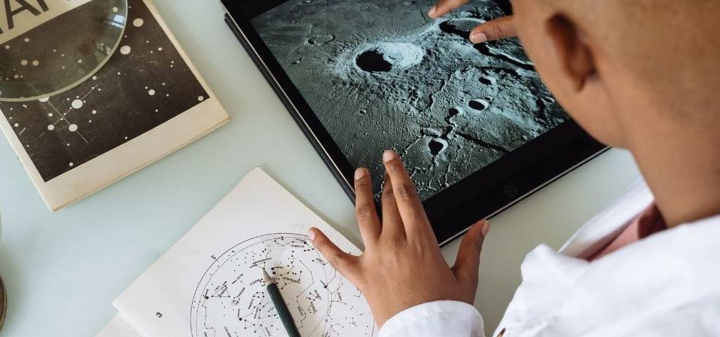 Garcon regardant les cratèresde la lune sur une tablette