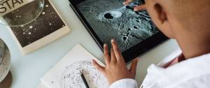 Garcon regardant les cratèresde la lune sur une tablette