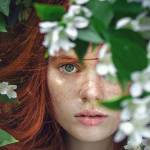Jeune femme rousse apparaissant dans des feuilles vertes et des fleurs blanches
